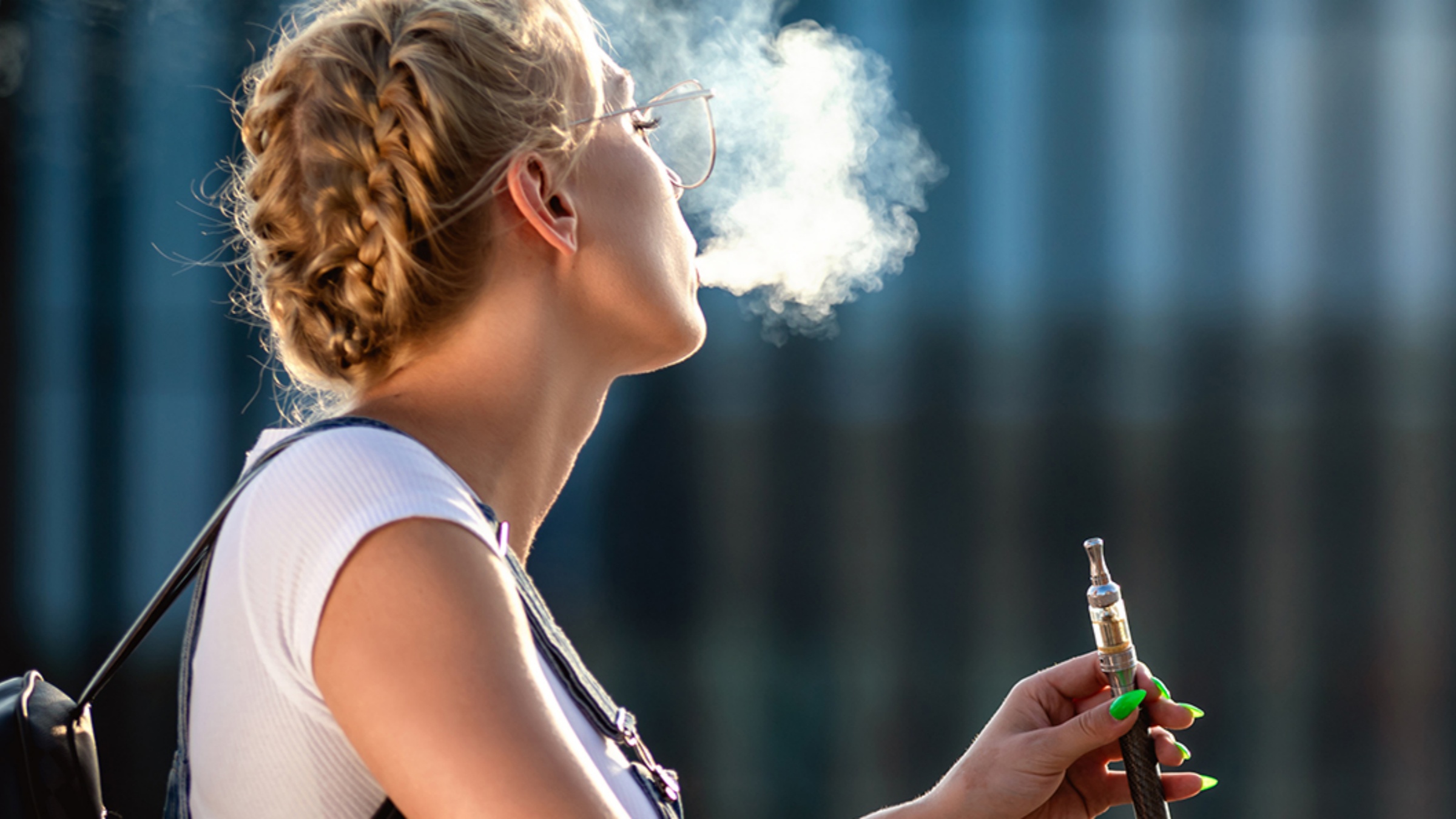 A young woman vaping in the sunlight.